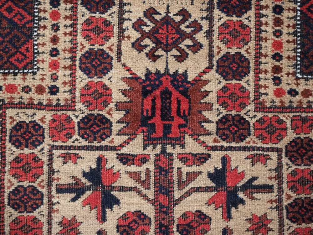 An antique Baluch wool prayer rug featuring a central mihrab arch, tree motifs, hand icons, and geometric borders in dark red, brown, and camel shades. View IX