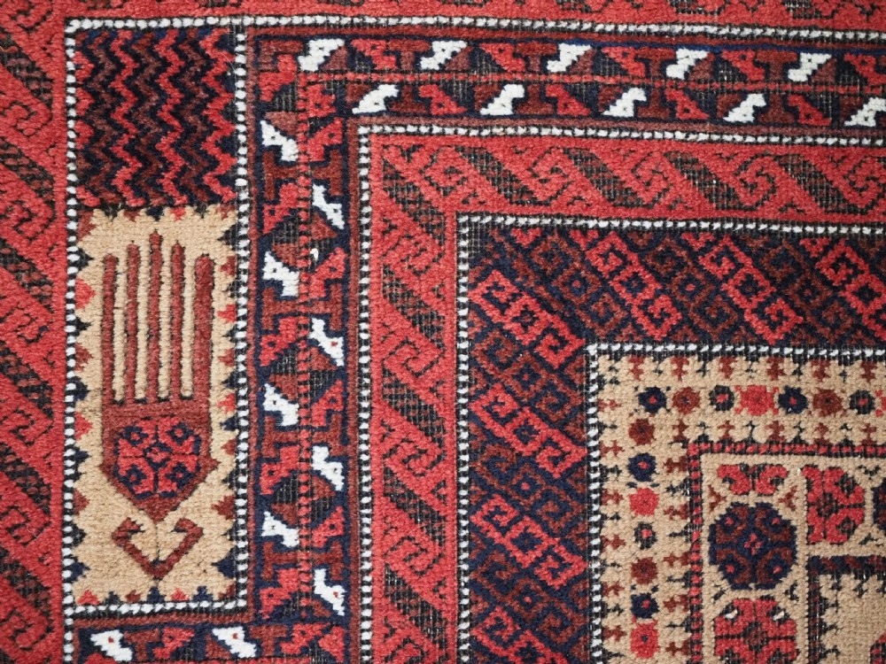 An antique Baluch wool prayer rug featuring a central mihrab arch, tree motifs, hand icons, and geometric borders in dark red, brown, and camel shades. View X