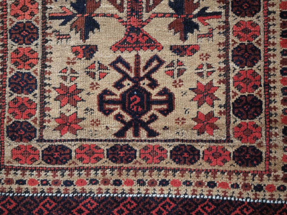 An antique Baluch wool prayer rug featuring a central mihrab arch, tree motifs, hand icons, and geometric borders in dark red, brown, and camel shades. View XII