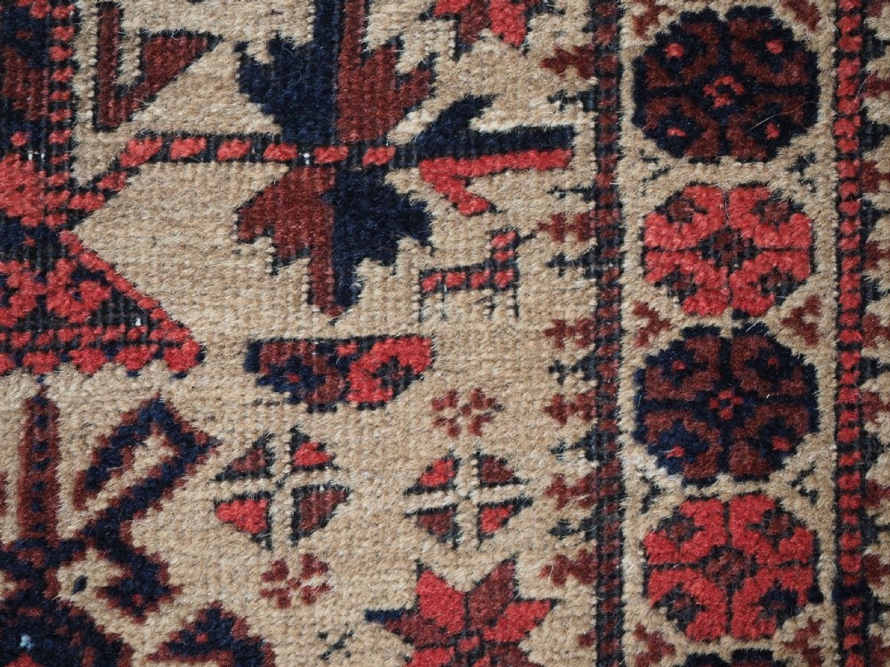 An antique Baluch wool prayer rug featuring a central mihrab arch, tree motifs, hand icons, and geometric borders in dark red, brown, and camel shades. View XIII
