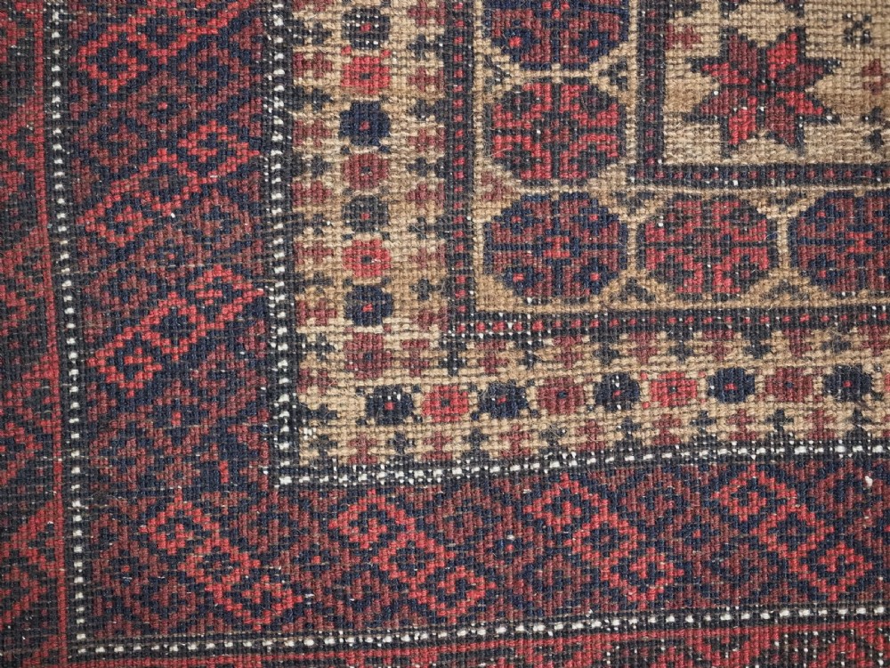 An antique Baluch wool prayer rug featuring a central mihrab arch, tree motifs, hand icons, and geometric borders in dark red, brown, and camel shades. View XV
