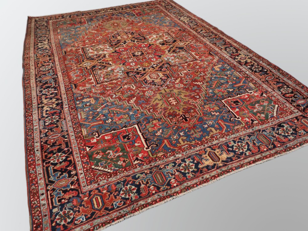 An antique hand-knotted wool Heriz carpet featuring a large central geometric medallion in rust red, navy blue, and cream surrounded by detailed geometric borders. View II