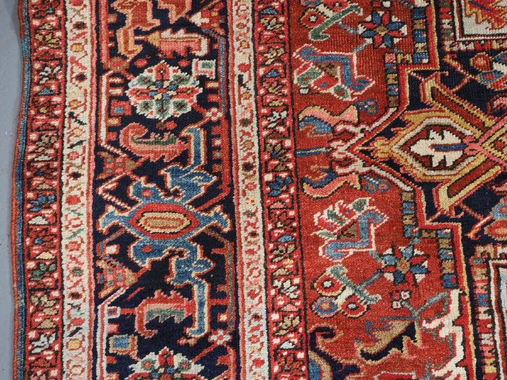 An antique hand-knotted wool Heriz carpet featuring a large central geometric medallion in rust red, navy blue, and cream surrounded by detailed geometric borders. View VIII