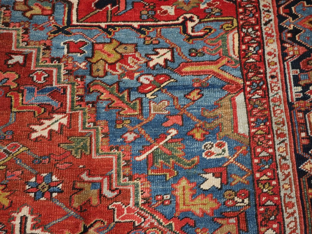 An antique hand-knotted wool Heriz carpet featuring a large central geometric medallion in rust red, navy blue, and cream surrounded by detailed geometric borders. View XII