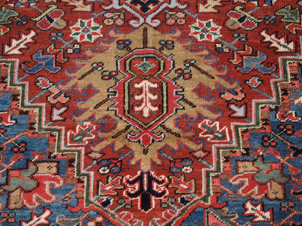 An antique hand-knotted wool Heriz carpet featuring a large central geometric medallion in rust red, navy blue, and cream surrounded by detailed geometric borders. View XV