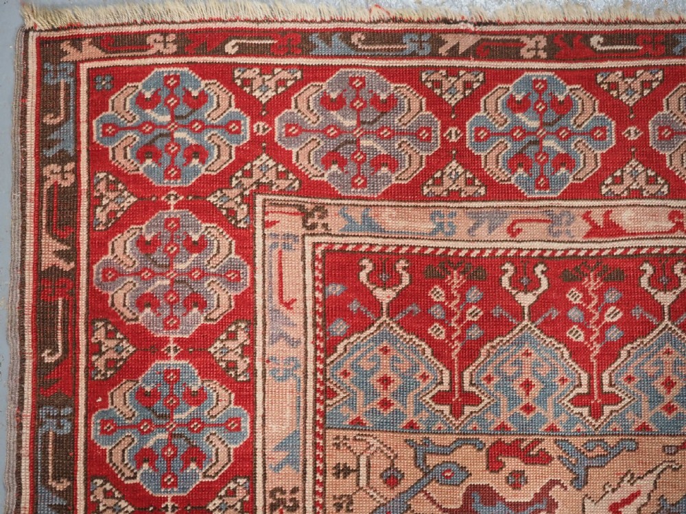 A hand-knotted wool prayer rug with a blue central column niche motif framed by beige spandrels and a red geometric border. View VI