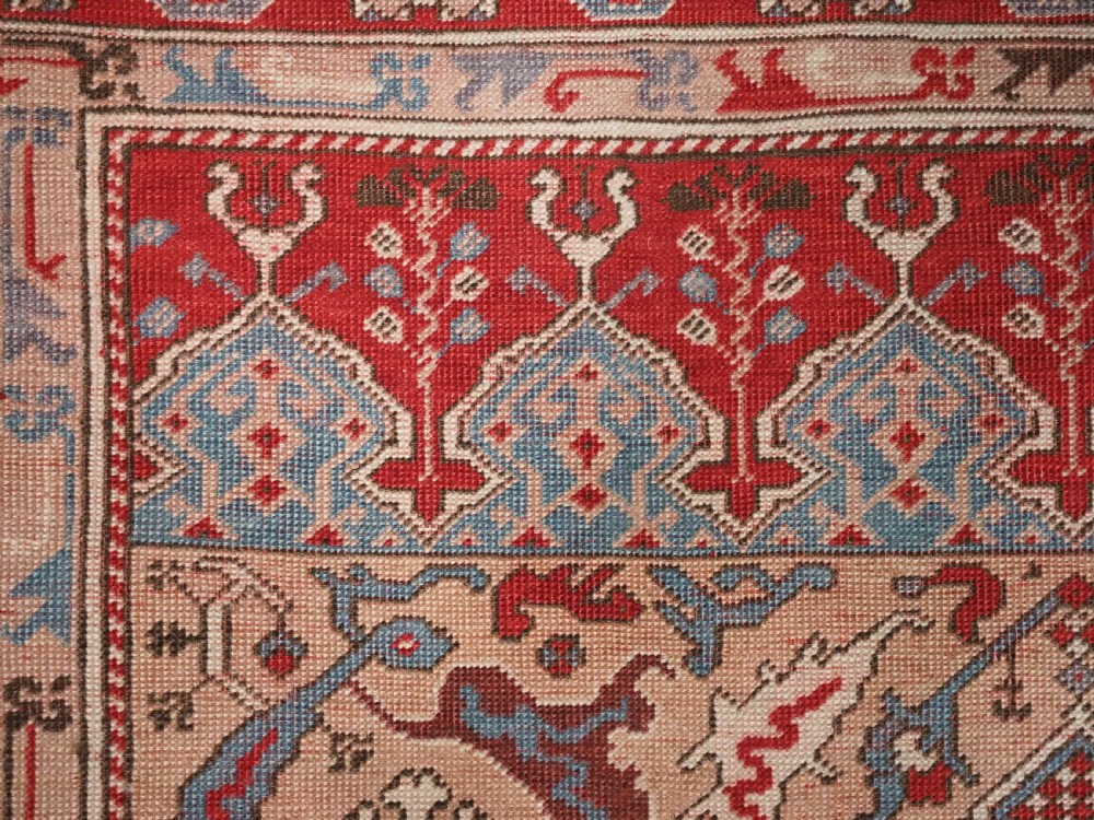 A hand-knotted wool prayer rug with a blue central column niche motif framed by beige spandrels and a red geometric border. View IX