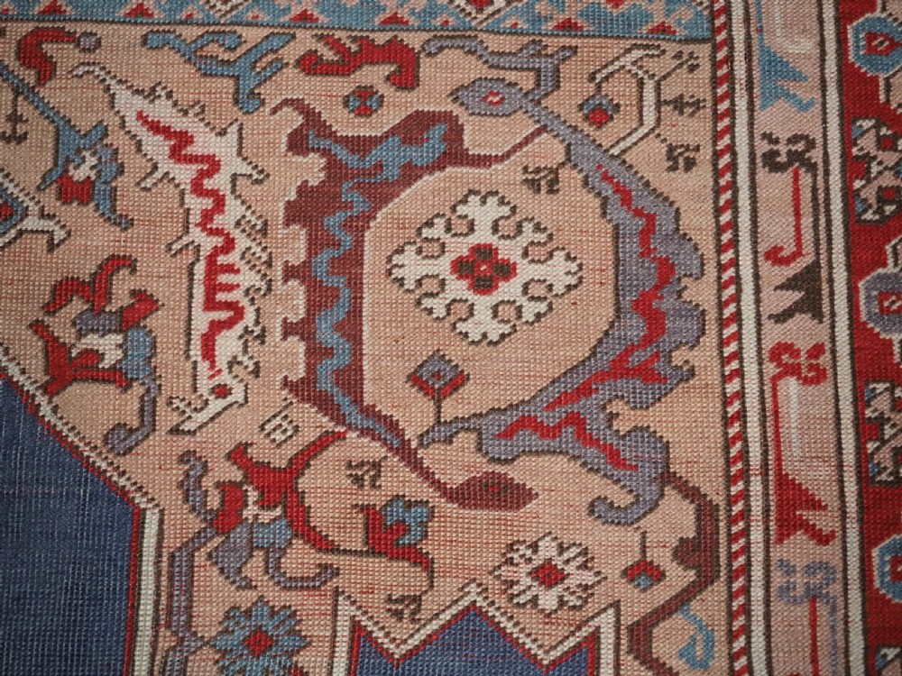 A hand-knotted wool prayer rug with a blue central column niche motif framed by beige spandrels and a red geometric border. View XI