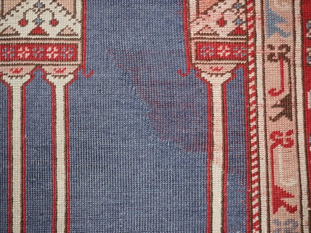 A hand-knotted wool prayer rug with a blue central column niche motif framed by beige spandrels and a red geometric border. View XIV