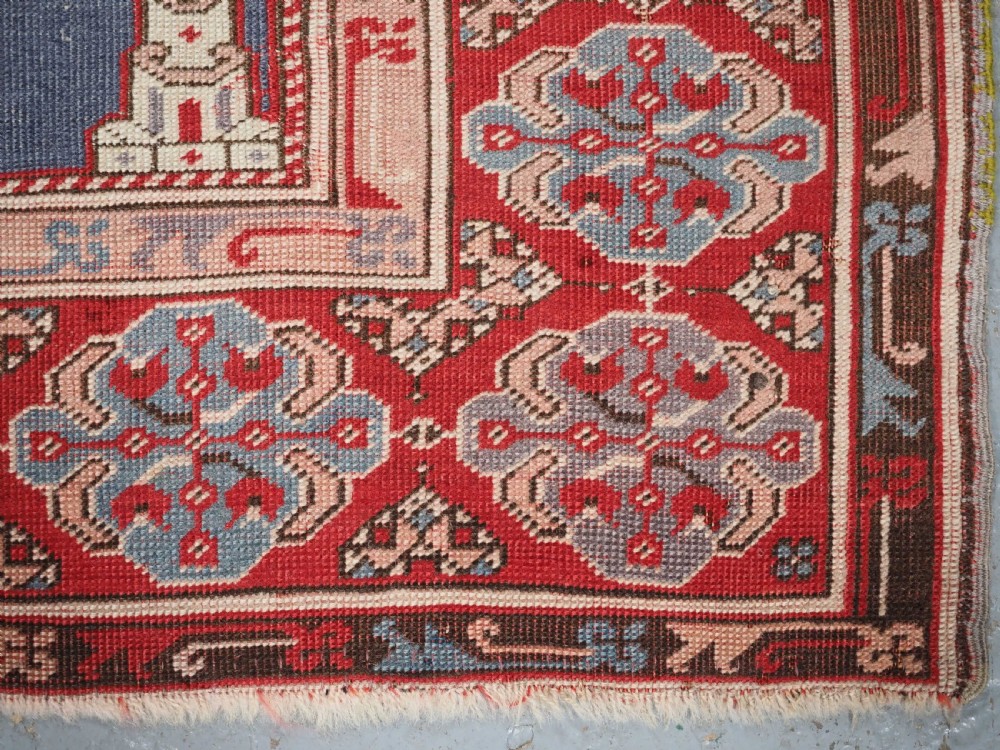 A hand-knotted wool prayer rug with a blue central column niche motif framed by beige spandrels and a red geometric border. View XV