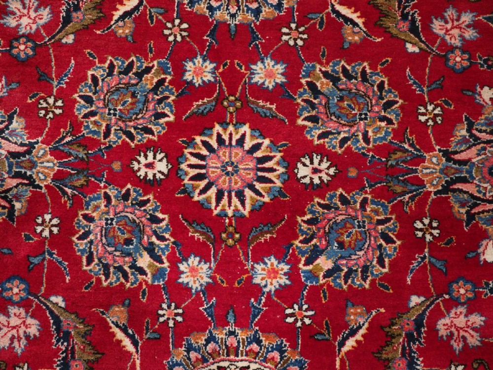 A large hand-knotted Kashan wool carpet featuring an intricate all-over floral pattern on a rich red field framed by a navy blue patterned border. View XI
