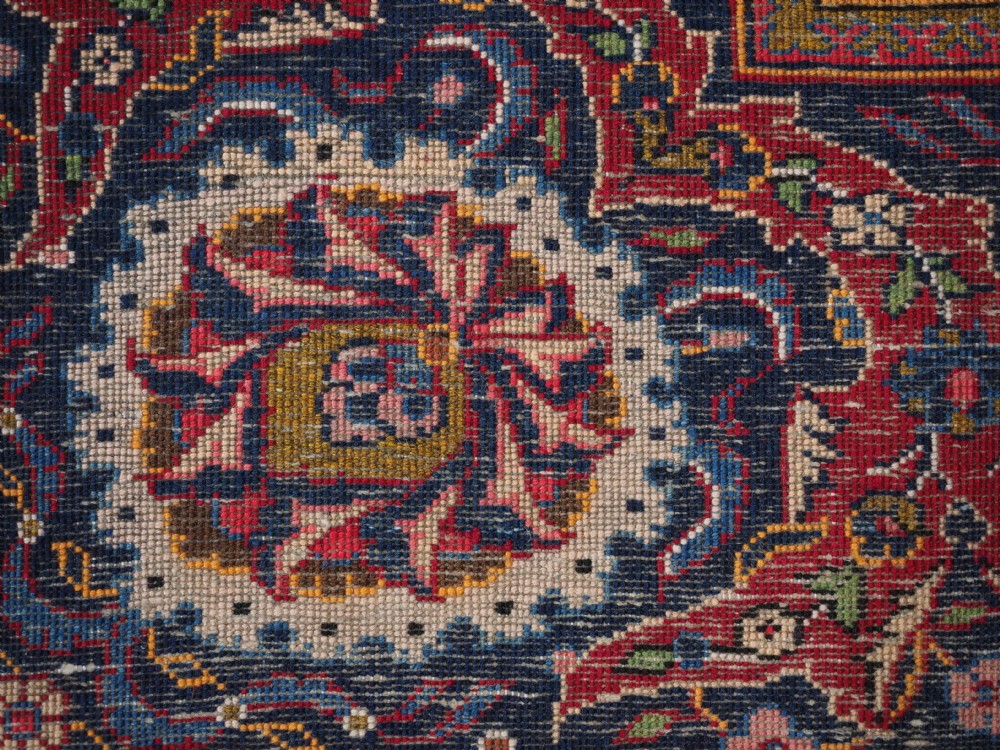 A large hand-knotted Kashan wool carpet featuring an intricate all-over floral pattern on a rich red field framed by a navy blue patterned border. View XV