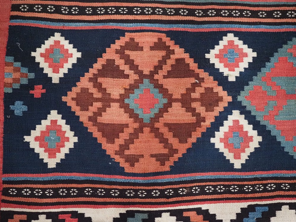An antique Shahsavan wool flatweave kilim rug featuring geometric diamond motifs in red, navy blue, terracotta, and light blue tones. View IX