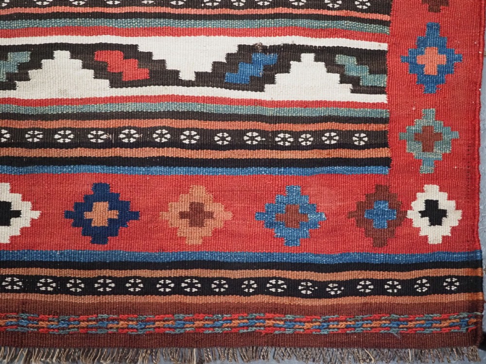 An antique Shahsavan wool flatweave kilim rug featuring geometric diamond motifs in red, navy blue, terracotta, and light blue tones. View XII