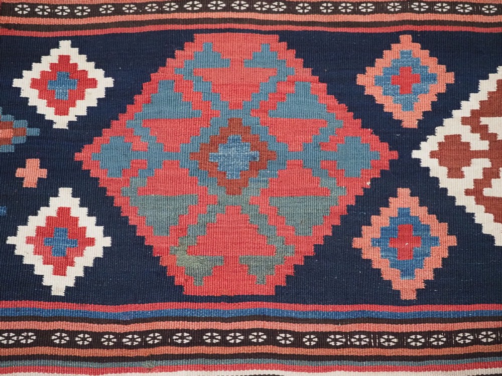 An antique Shahsavan wool flatweave kilim rug featuring geometric diamond motifs in red, navy blue, terracotta, and light blue tones. View XIV