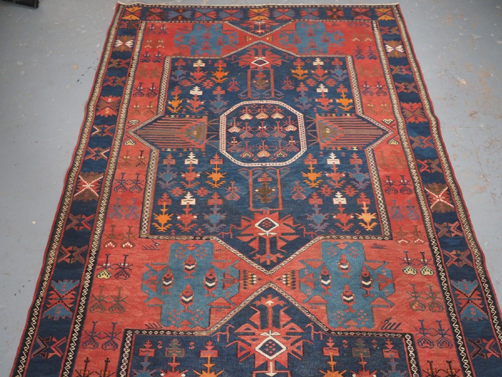 An antique flatweave Caucasian Avar kilim runner featuring geometric octagonal medallions down a navy centre field framed by terracotta and blue patterned borders. View II
