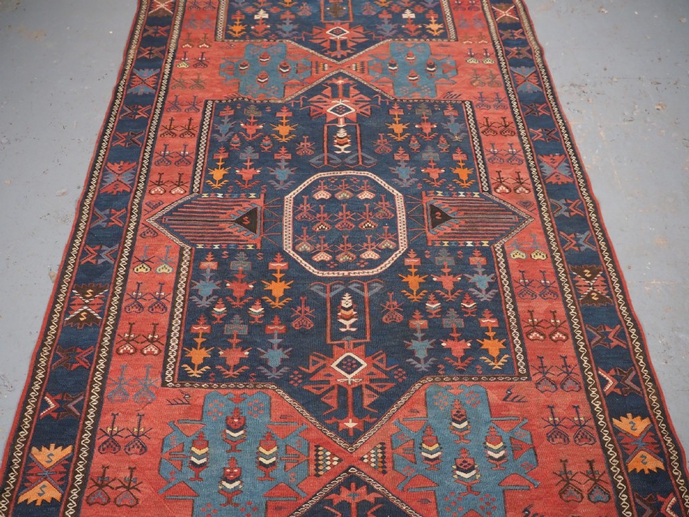 An antique flatweave Caucasian Avar kilim runner featuring geometric octagonal medallions down a navy centre field framed by terracotta and blue patterned borders. View III