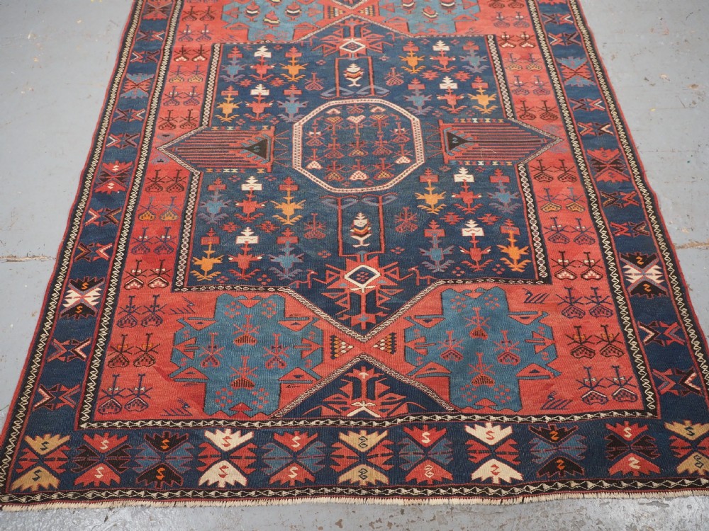 An antique flatweave Caucasian Avar kilim runner featuring geometric octagonal medallions down a navy centre field framed by terracotta and blue patterned borders. View IV