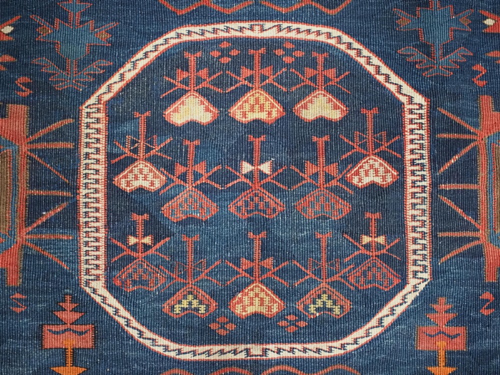 An antique flatweave Caucasian Avar kilim runner featuring geometric octagonal medallions down a navy centre field framed by terracotta and blue patterned borders. View IX