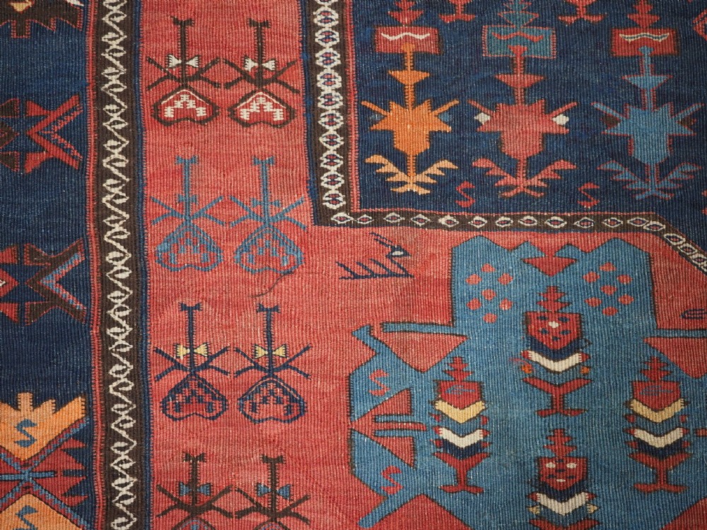 An antique flatweave Caucasian Avar kilim runner featuring geometric octagonal medallions down a navy centre field framed by terracotta and blue patterned borders. View XII