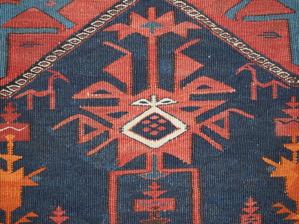 An antique flatweave Caucasian Avar kilim runner featuring geometric octagonal medallions down a navy centre field framed by terracotta and blue patterned borders. View XIV