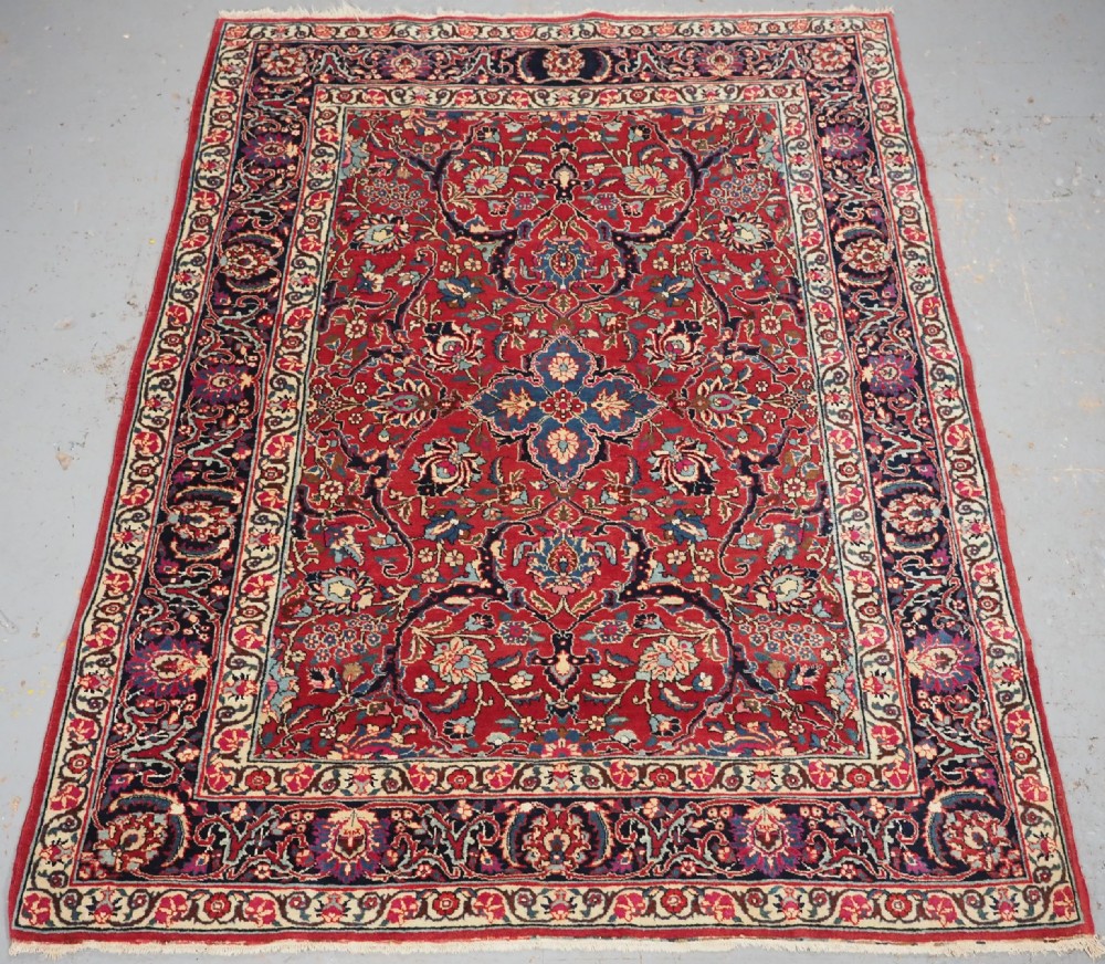 A hand-knotted Tabriz wool rug featuring a blue central star medallion surrounded by floral scrollwork in red, cream, and navy blue with an ornate border.