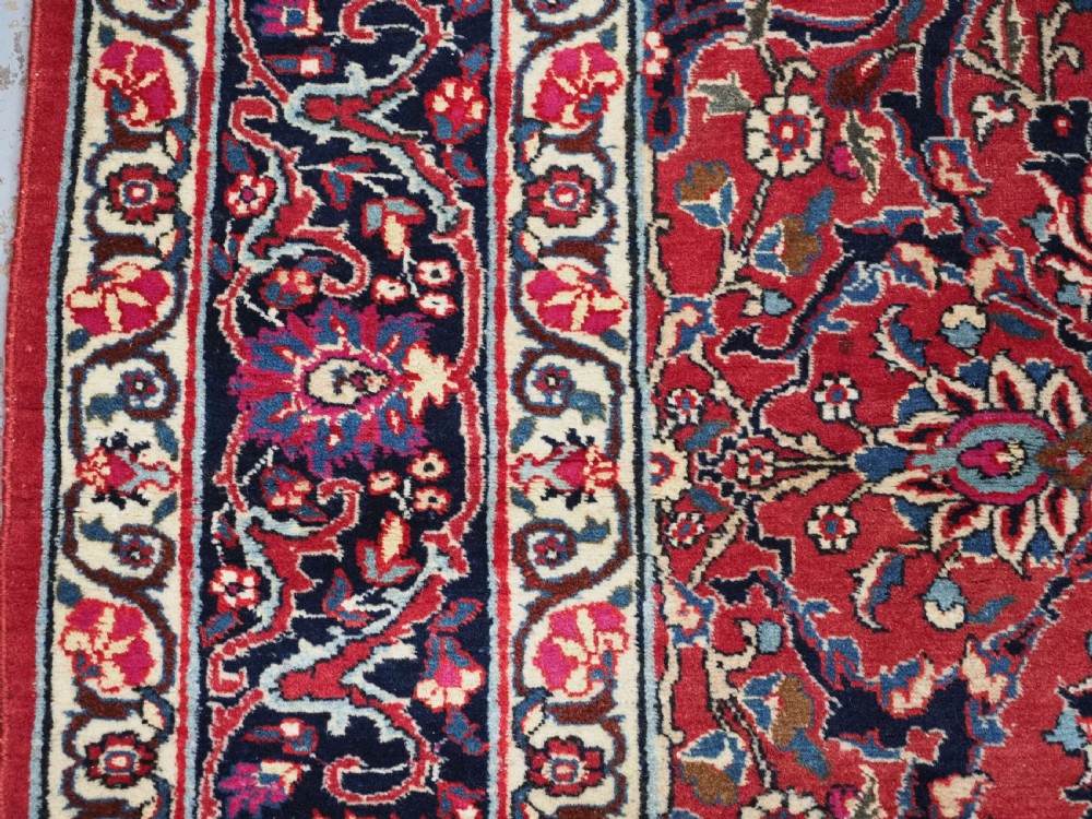 A hand-knotted Tabriz wool rug featuring a blue central star medallion surrounded by floral scrollwork in red, cream, and navy blue with an ornate border. View VII