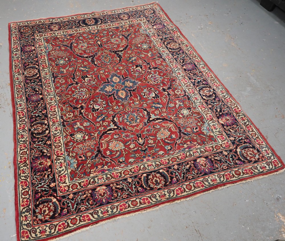 An antique hand-knotted Persian Tabriz wool rug featuring a dark navy central medallion surrounded by a red floral field and decorative navy borders. View II