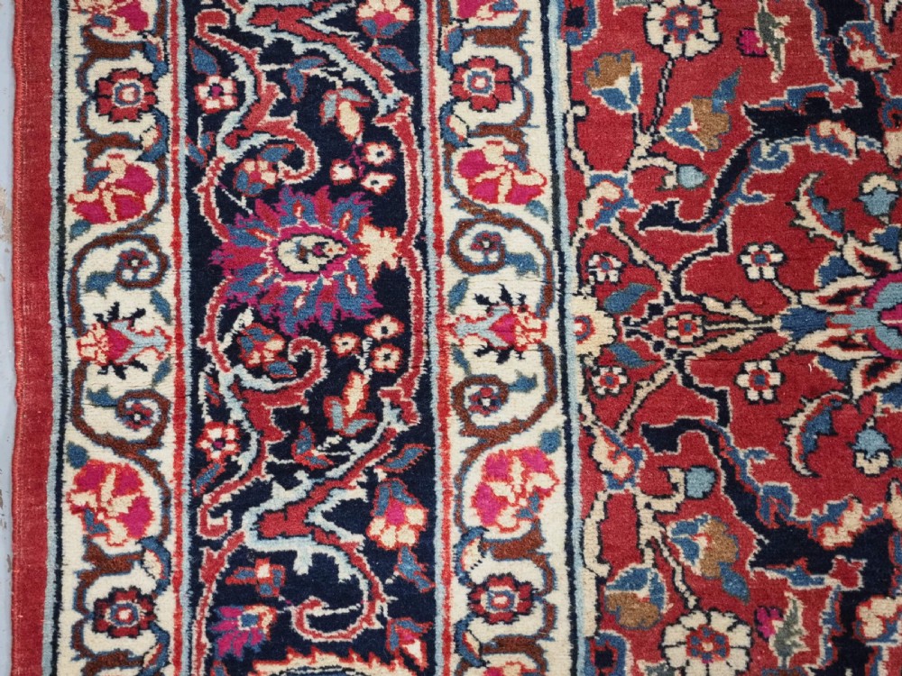 An antique hand-knotted Persian Tabriz wool rug featuring a dark navy central medallion surrounded by a red floral field and decorative navy borders. View VII