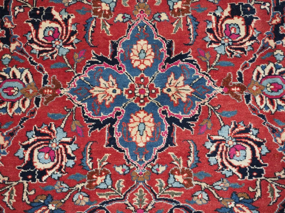 An antique hand-knotted Persian Tabriz wool rug featuring a dark navy central medallion surrounded by a red floral field and decorative navy borders. View IX