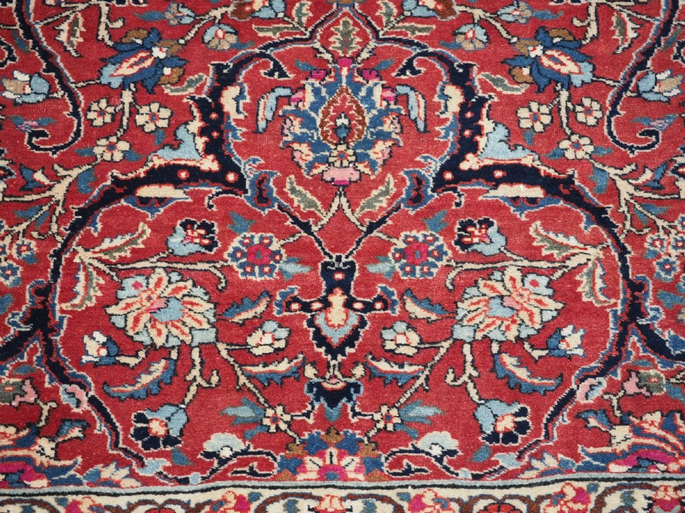An antique hand-knotted Persian Tabriz wool rug featuring a dark navy central medallion surrounded by a red floral field and decorative navy borders. View X