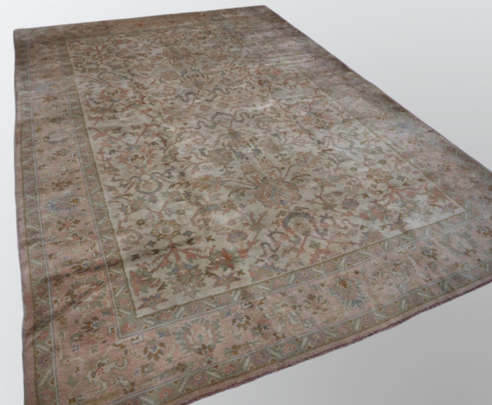 An antique Turkish Oushak wool carpet featuring a soft pink and beige ground decorated with pastel floral palmette patterns and multi-layered borders. View II