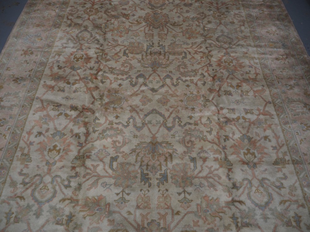 An antique Turkish Oushak wool carpet featuring a soft pink and beige ground decorated with pastel floral palmette patterns and multi-layered borders. View VII