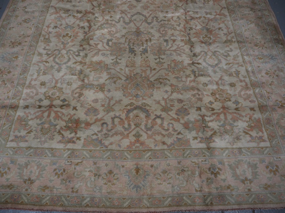 An antique Turkish Oushak wool carpet featuring a soft pink and beige ground decorated with pastel floral palmette patterns and multi-layered borders. View VIII