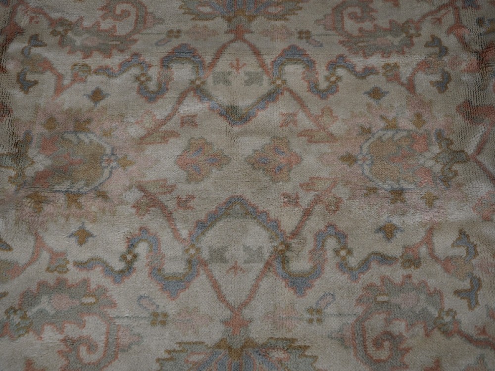 An antique Turkish Oushak wool carpet featuring a soft pink and beige ground decorated with pastel floral palmette patterns and multi-layered borders. View XIII