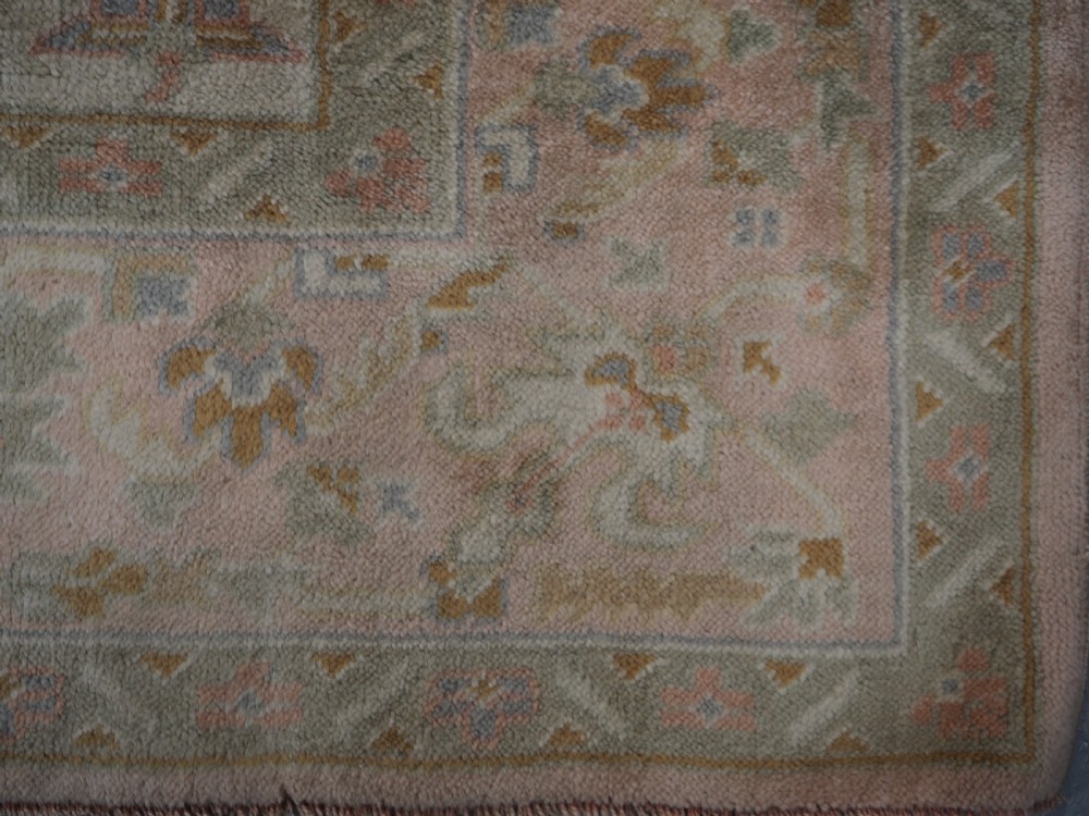 An antique Turkish Oushak wool carpet featuring a soft pink and beige ground decorated with pastel floral palmette patterns and multi-layered borders. View XVIII