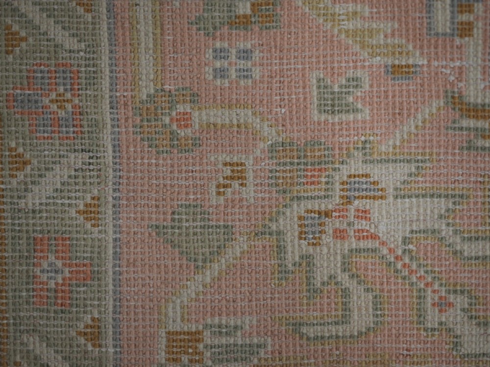 An antique Turkish Oushak wool carpet featuring a soft pink and beige ground decorated with pastel floral palmette patterns and multi-layered borders. View XIX