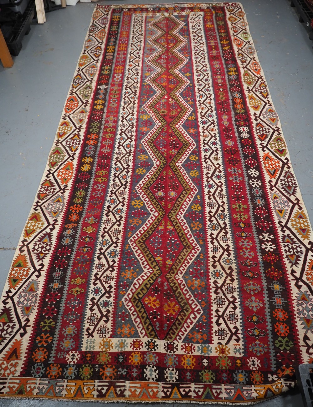 A large flatwoven antique Turkish Kayseri wool kilim rug featuring central red diamond medallions surrounded by geometric patterned borders. View III