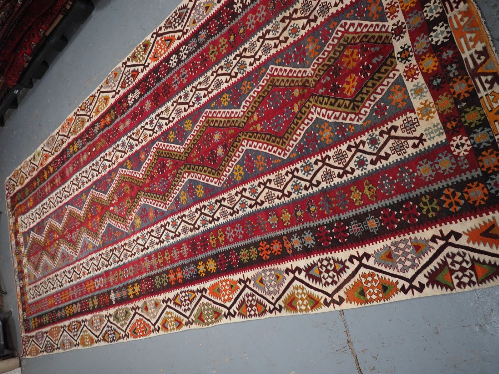 A large flatwoven antique Turkish Kayseri wool kilim rug featuring central red diamond medallions surrounded by geometric patterned borders. View IV