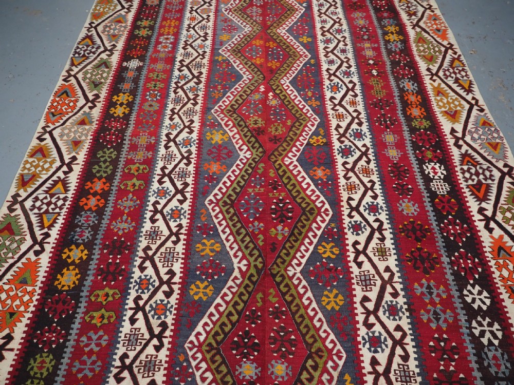 A large flatwoven antique Turkish Kayseri wool kilim rug featuring central red diamond medallions surrounded by geometric patterned borders. View VI