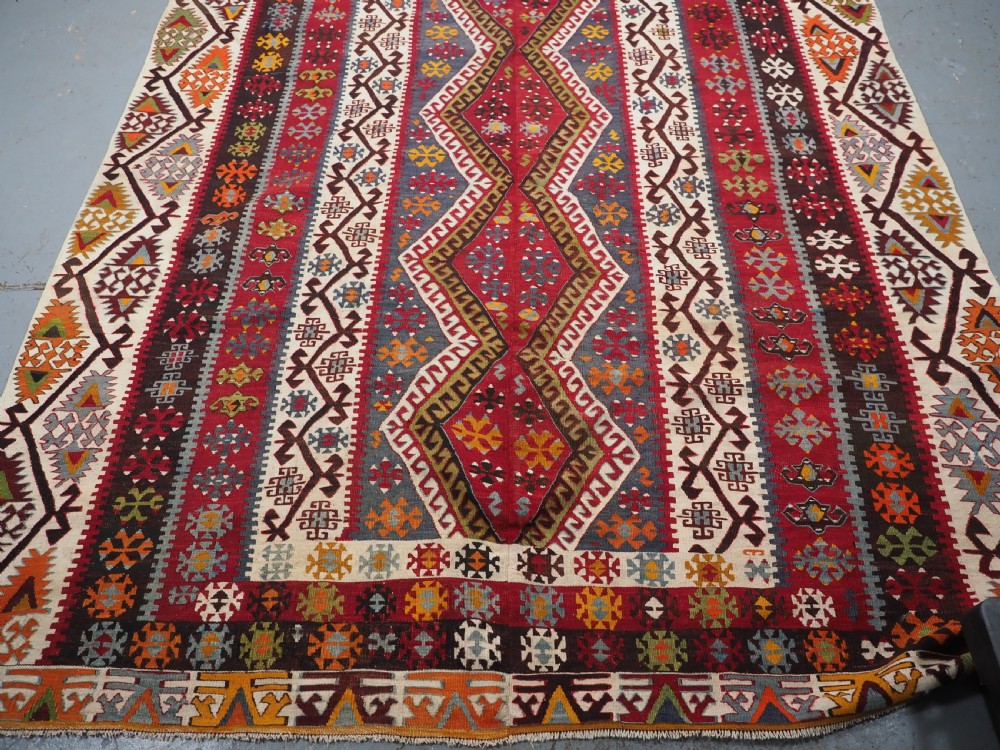 A large flatwoven antique Turkish Kayseri wool kilim rug featuring central red diamond medallions surrounded by geometric patterned borders. View VII