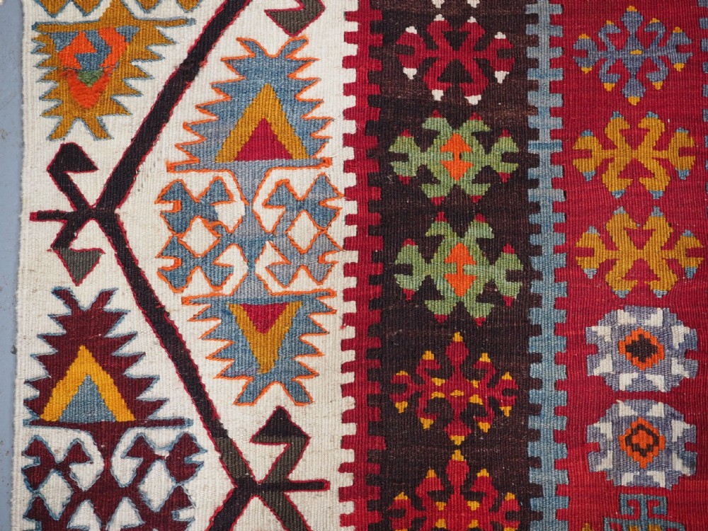 A large flatwoven antique Turkish Kayseri wool kilim rug featuring central red diamond medallions surrounded by geometric patterned borders. View IX
