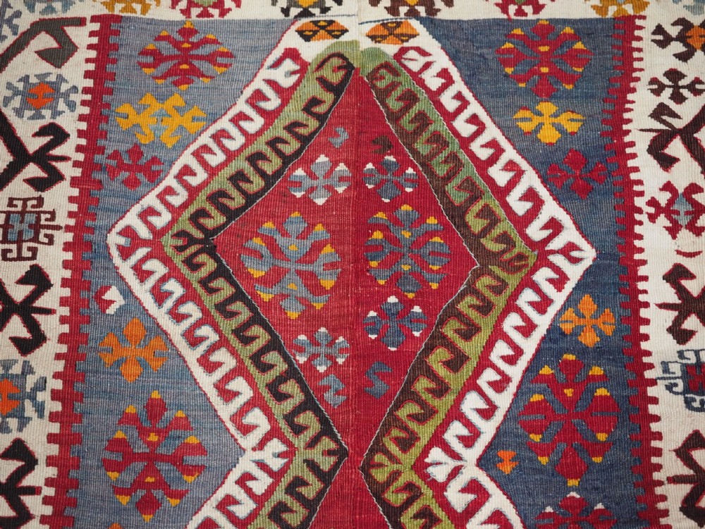 A large flatwoven antique Turkish Kayseri wool kilim rug featuring central red diamond medallions surrounded by geometric patterned borders. View X
