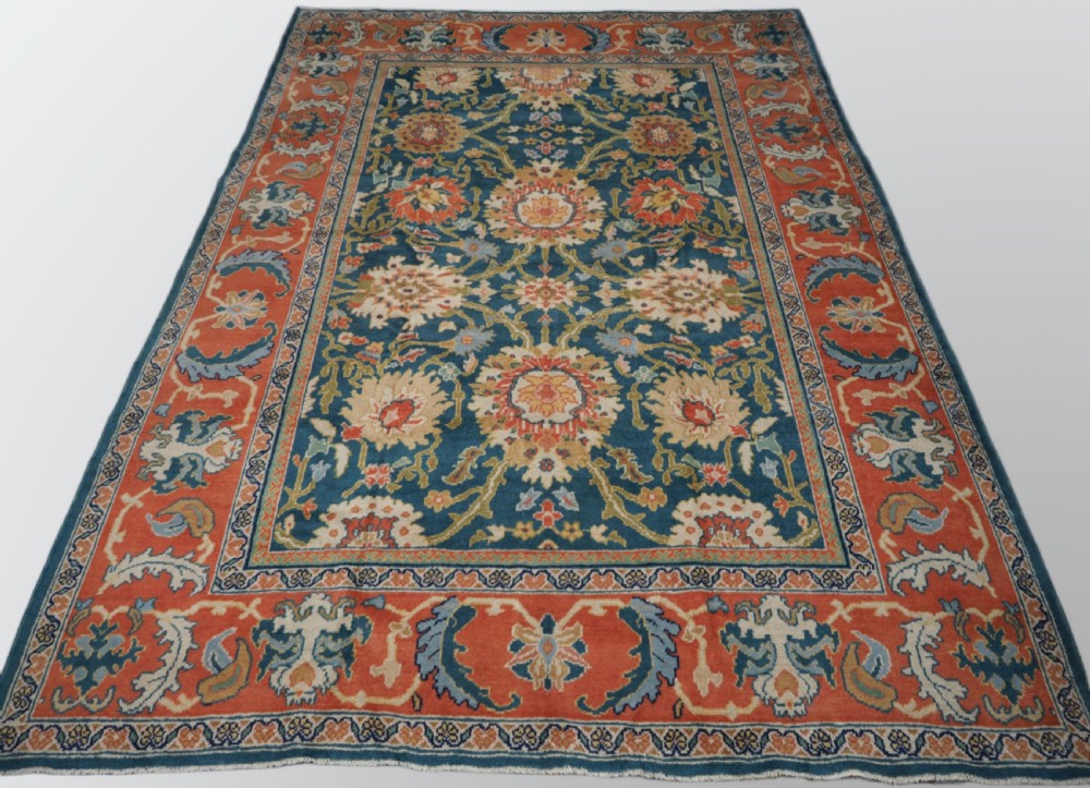 A hand-knotted Persian Mahal carpet with a central blue field decorated with floral palmettes and framed by a wide terracotta border.