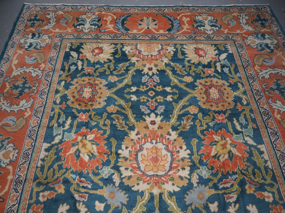 A hand-knotted Persian Mahal carpet with a central blue field decorated with floral palmettes and framed by a wide terracotta border. View V