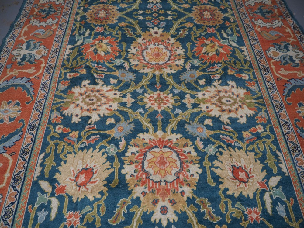 A hand-knotted Persian Mahal carpet with a central blue field decorated with floral palmettes and framed by a wide terracotta border. View VI