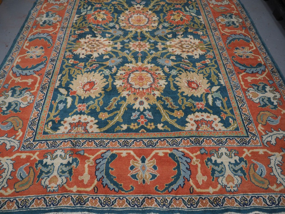 A hand-knotted Persian Mahal carpet with a central blue field decorated with floral palmettes and framed by a wide terracotta border. View VII