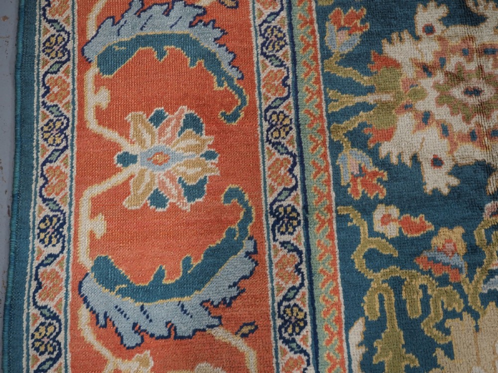 A hand-knotted Persian Mahal carpet with a central blue field decorated with floral palmettes and framed by a wide terracotta border. View IX