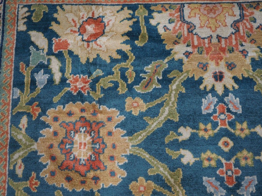 A hand-knotted Persian Mahal carpet with a central blue field decorated with floral palmettes and framed by a wide terracotta border. View X