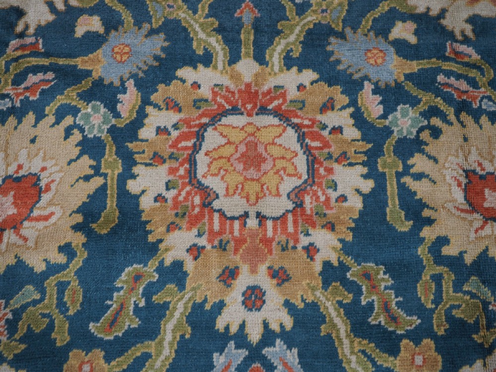 A hand-knotted Persian Mahal carpet with a central blue field decorated with floral palmettes and framed by a wide terracotta border. View XIV